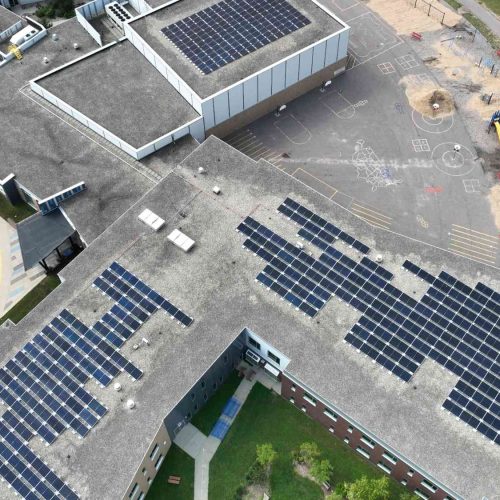 Aerial image showing completed rooftop solar arrays across the Bridges Elementary School buildings and playground areas.