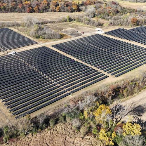 Aerial view of the Rock Lake Solar project in Waterloo, Wisconsin, showing rows of solar panels arranged in multiple large sections surrounded by fall foliage.