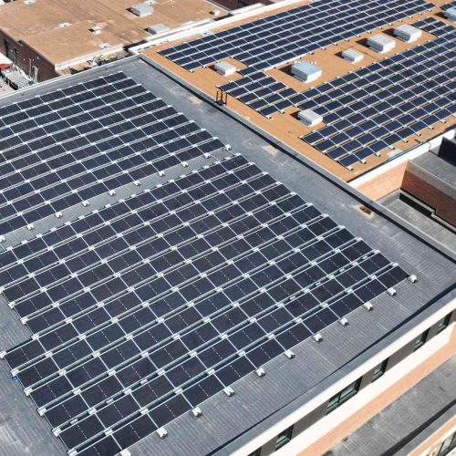 Aerial view of rooftop solar panels installed across multiple sections of a commercial building roof.