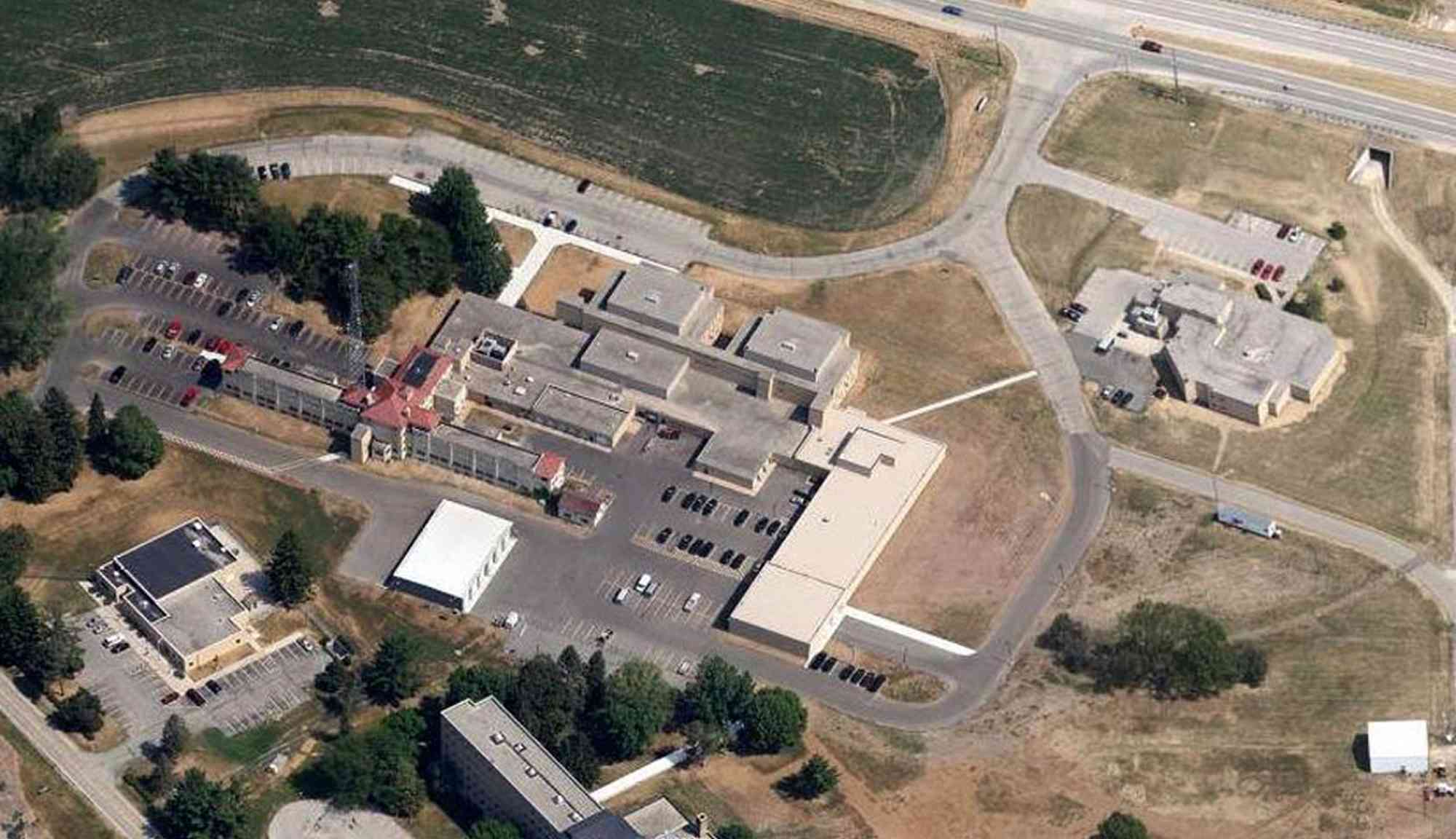 Aerial view of a large institutional campus showing multiple connected buildings, parking areas, and surrounding roadways.