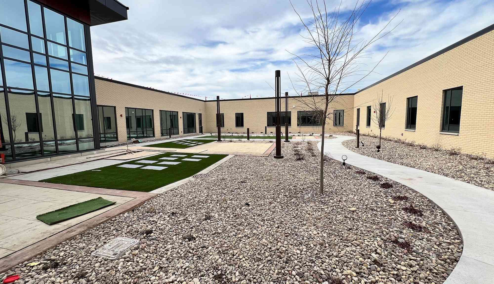 Interior courtyard view with landscaped stone beds, walkways, and surrounding building walls.