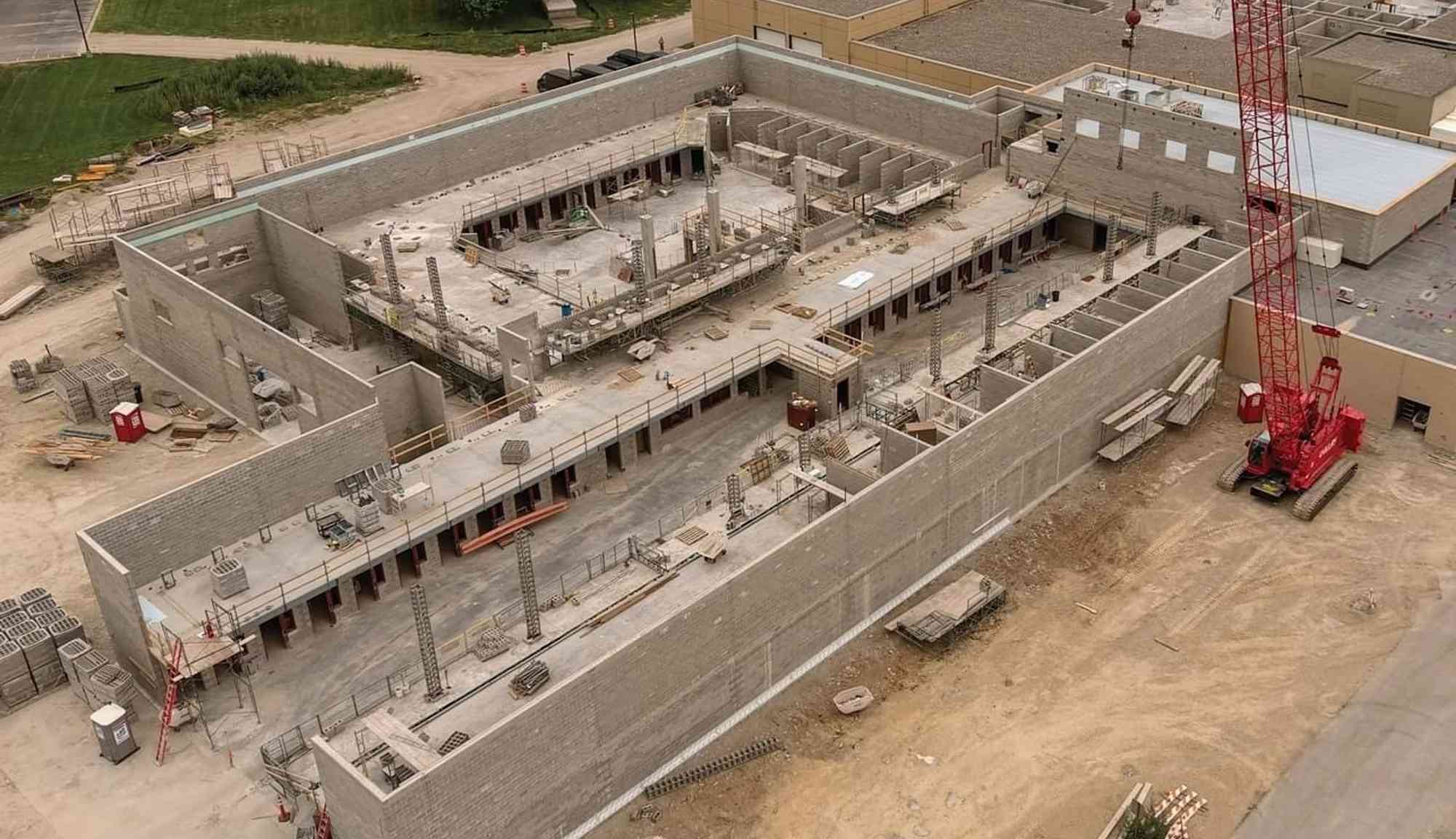 Aerial view of a multi-story building under construction with interior rooms, scaffolding, and structural walls visible.