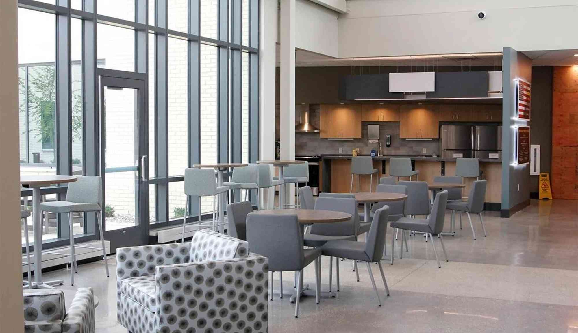 Interior lobby space with seating, tables, and natural light from large windows.